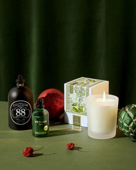 The classic No.88 Cologne Shaker alongside Vetiver Vert eau de Parfum and Perfecto Fino Candle on green with Christmas Baubles, red berries and a dark green velvet curtain behind.