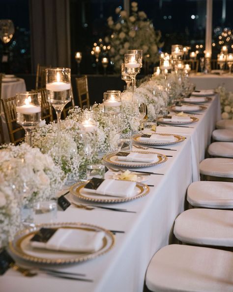 Transform your reception into a regal affair with intricate gold tablescape details. White florals, statement candles and the gold accents create an ambiance of opulent elegance. ✨   #weddingtablescape #tabelscapedesign #weddingreception #weddinginspo #weddingdetails #weddingdecor #weddingstyle #weddingplanner #nycweddings #overthemoon #stylemepretty #luxuryweddings #caratsandcake #alinatoevents Reception Table Decorations Candles, Elegant Outdoor Wedding Reception Table Arrangements, Classic Elegant Wedding Table Setting, Timeless Wedding Tablescape, White Wedding Design, Neutral Wedding Decorations Receptions, White Floral Wedding Table Decor, Wedding Themes White And Gold, White And Gold Wedding Aesthetic