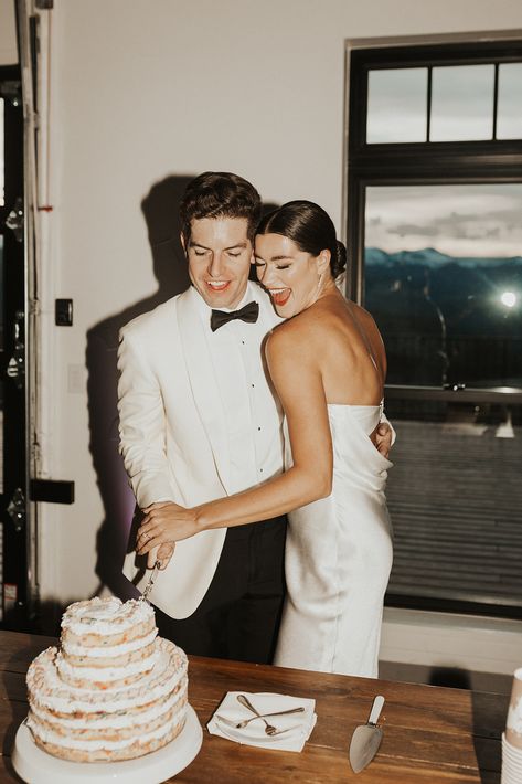 A groom in a white suit with black bowtie, and a bride with a sleek bun and cocktail dress cut a milk bar cake at their wedding. Reception Dress Change, Milk Bar Cake, Cream Color Palette, Wedding Photo List, Birch Wedding, Bar Cake, Wedding Shot List, Hunter Wedding, 2025 Goals