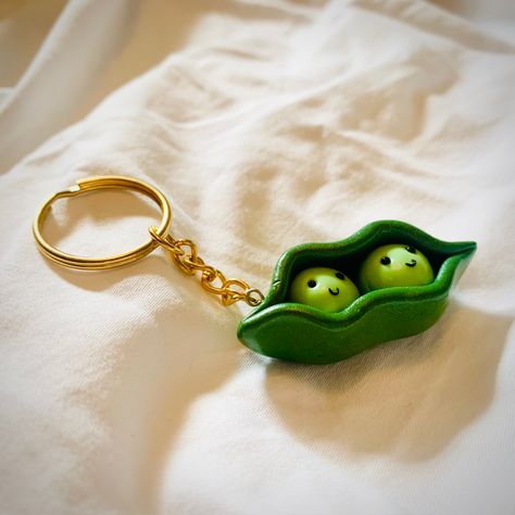 Handmade peas in a pod key ring or charm, intricately crafted with polymer clay and glazed with a gloss varnish. Approx. 5cm in length All charms are made with eye pin built in. On top of this I have multiple options for additional attachment methods- a lobster clasp phone charm, or a silver / gold plated key ring. These are made to order, so feel free to message me with any questions or individual requests! #peasinapod #keyring #polymerclay #etsy #handmade Clay Peas In A Pod, Polymer Clay Key Ring Ideas, Polymer Clay Keyring Ideas, Polymer Clay Pins Ideas, Air Dry Clay Ideas Keychain, Polymer Clay Ring Ideas, Polymer Clay Keychains Diy, Clay Diy Gifts, Polymer Clay Key Chains