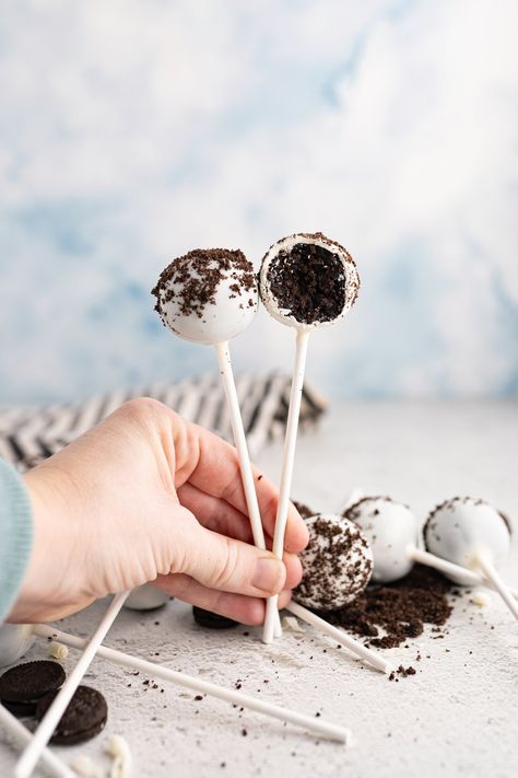 A hand holding two cookies and cream cake pops. Starbucks Cookies And Cream, Cookies And Cream Cake Pops, Cookie Pops Recipe, Starbucks Cookies, Starbucks Cake Pops, Starbucks Cake, Cooking With Karli, White Chocolate Candy, Cookies And Cream Cake