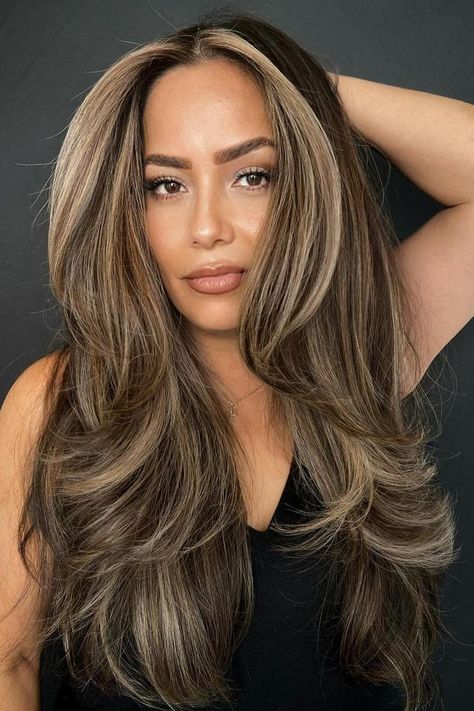 Long layered hair with face-framing highlights creates a dynamic look, adding movement and dimension. The blend of cool blonde streaks graces through rich brunette tones providing a sun-kissed effect. Loose waves enhance the texture, giving it a voluminous and flowing appearance.  // Photo Credit: Instagram @hairbyjess_1 Brunette And Highlights, Long Layered Hair With Balayage, Hair Color Ideas For Dark Features, Blonde Highlights Root Melt, Fall Balayage Blonde Brunette, Medium Layered Balayage Hair, Brunette Hair Face Framing Highlights, Hair Color Ideas On Black Hair, Different Colour Highlights