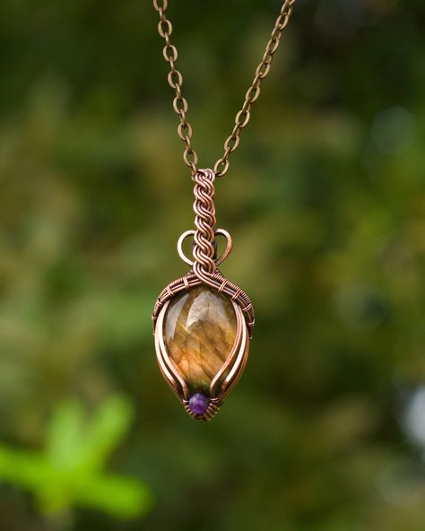 "This gemstone pendant features a flashy orange labradorite oval with a faceted royal purple amethyst accent. The crystal is wire wrapped in pure copper with a triple wire bail that is twisted into a Celtic braid design with minimal coverage on the front of the stone. The wire has been antiqued and hand polished for an antique look. This unisex pendant comes with an 18\" antique copper plated chain and lobster clasp. If you prefer a different length, let me know and I will gladly customize your chain for you. You can upgrade to a pure copper ball chain for $5. It ships for free in US in a gift box. If you are sending this as a gift to someone else, I will happily include a handwritten card with a message from you! Just let me know what you'd like to say." Diy Necklace Designs, Celtic Braid, Wire Wrapped Crystal Pendant, Wire Wrap Cabochon, Wire Jewelry Rings, Wire Wrap Jewelry Designs, Wire Wrapped Jewelry Diy, Instruções Origami, Wire Wrapped Crystal