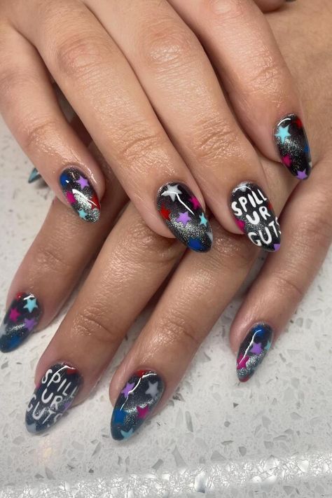 Dive into the galaxy with these almond-shaped nails featuring an interstellar explosion of colors. A cosmic blend of black, blue, and purple creates a celestial backdrop, accented by vibrant pops of white and red stars. A bold statement is made with the words SPILL UR GUTS inscribed across two nails, tying the mystic space theme with an edgy twist. The overall effect is a captivating nail art transformation that's out of this world! 🌌✨  // Photo Credit: Instagram @manis.by.mari Oliva Rodrigo Nails, Guts Nails Olivia Rodrigo, Olivia Rodrigo Nail Inspo Guts, Guts Tour Nails, Olivia Rodrigo Nails Ideas, Olivia Rodrigo Nails Ideas Guts, Guts Nails, Olivia Nails, Olivia Rodrigo Nails