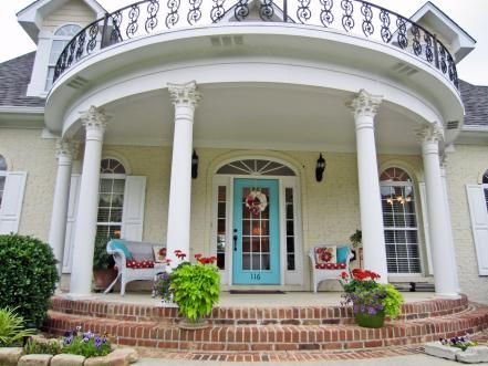 A cheery blue front door and large demilune front porch with Corinthian columns give this Greek revival-style home in Huntsville, Ala., timeless curb appeal. The front door color pops amongst a wall of large windows to create an obvious front entry space. Round Porch, Corinthian Columns, Porch Kits, Ocean Front Homes, Building A Porch, Porch Columns, Door Picture, Enclosed Porches, Door Paint