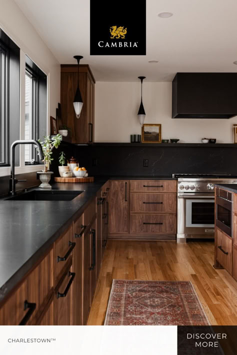 Rustic charm and bold contrast come together resulting in this inviting kitchen space. The black quartz countertops and dark wood cabinets pair perfectly together for a cozy and sophisticated feel, while the natural light from the windows emphasizes the elevated details. 

Click for more of Cambria Charlestown quartz design. 

Photographer: Chelsie Lopez 
Designer: Construction2Style Wood Cabinet Dark Countertop, Dark Stained Kitchen Cabinets Black Countertops, Dark Wood Cabinets With Black Countertop, Dark Brown Kitchen Cabinets With Black Stainless Appliances, Dark Wood Cabinets Black Countertops, Wood Kitchen Cabinets Dark Countertop, Natural Cabinets With Black Countertops, Natural Wood Cabinets Black Countertops, Black Backsplash Wood Cabinets