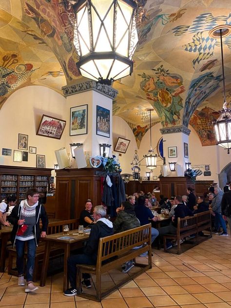 Patrons dining and socializing in the historic interior of Munich's Hofbräuhaus with vibrant frescoes and traditional decor. German Culture Aesthetic, Germany People, Germany Culture, Black Forrest, Europe Culture, Summer Abroad, Brewery Design, Beautiful Germany, German Architecture