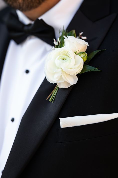 White ranunculus boutonniere with spray rose, genestra, and greenery accents. Stems partially wrapped in black velvet ribbon. PC: Ann Coen https://www.anncoen.com/photography Boutonniere Wrap Ideas, Groomsman Flowers Groom Boutonniere, Boutinaire Ideas, White Garden Rose Boutonniere, Ranaculus Boutonniere Groomsmen, Modern Groom Boutonniere, Tulip Boutineer Groomsmen, Winter Wedding Boutonniere White, Neutral Wedding Boutonniere