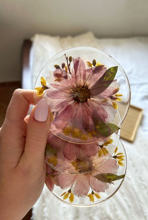 Elevate your home decor with this set of handmade resin coasters featuring real dried purple and yellow flowers. Each coaster is a unique work of art, with floral patterns preserved in the clear resin and a hand-painted golden rim adding sophistication. Protect your surfaces in style with these beautiful and practical coasters, perfect for any occasion. Please note each coaster is unique and may have slight variations in color and pattern. Visit Gold and Spice on Etsy for more! Glitter Gift Ideas, Purple And Yellow Flowers, Dried Flower Jewelry, Flower Coasters, Temple Decor, Pressed Flower Crafts, Floral Preservation, Bouquet Preservation, Diy Resin Projects