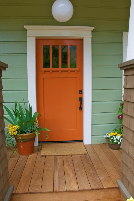 This bright orange door's sturdy structural elements stay true to the home's Craftsman style. While the home's exterior is a sage green hue, designer John Gidding swings to the other side of the color wheel for a front door color with true contrast. Orange Front Door, Exterior Door Trim, Orange Front Doors, Curbside Appeal, Unique Front Doors, Best Front Doors, Orange Door, Front Door Paint Colors, Potting Table