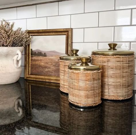 Organize your space in pure style with our Rattan Wrapped Storage Canisters, Set of 4. This canister comes in a set of four sizes, each with rattan-wrapped detailing, a brass finish, and lids for easy storing. These gorgeous canisters are great for storing and displaying and will look great in any farmhouse home! Cannister Ideas Kitchen, Pantry Canisters, Shabby Chic Antiques, Model Accessories, Backyard House, Storage Canisters, Vintage Baskets, Antique Farmhouse, Canister Sets