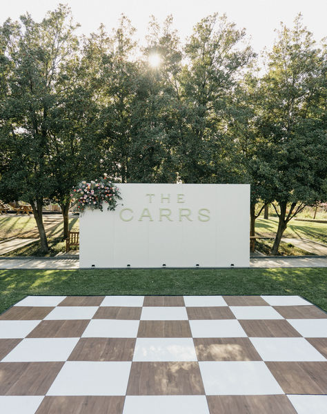 Wooden and white checkered dance floor with stunning custom wall! Perfect for welcoming guests to dance!! Stunning and unique flooring for Dallas wedding!  #socialllamaevents #dallaswedding #dancefloor #customdancefloor #weddingrentals #weddingdeocr #weddinginspo #weddingfloor #customrentals #dallasrentals #customwedding #socialllama #customrentals #weddinginspiration Boho Wedding Dance Floor Ideas, Checkers Dance Floor, Rugs As Dance Floor Wedding, Wedding Floor Vinyl, How To Build A Dance Floor, Checkered Dance Floor Outdoor Wedding, Wedding Decor Dance Floor, Wedding Dance Floor Alternatives, Wooden Dance Floor Wedding