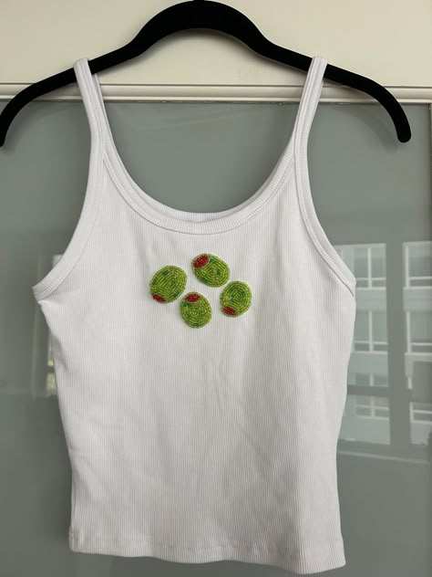 Custom made, hand beaded Tank or Tee!  You can select either a ribbed cami, ribbed high neck tank, ribbed scoop neck tank, or a basic tee (see pictures). If you would like a color other than white please let me know the color and I will let you know if it is available (and will send you a pic of color for your approval). The design will be stitched directly onto the fabric with a safety backing.  Please send me an inspo pic of what design you would like. A screenshot would be perfect! I will send you my sketch before starting the stitching. I can pretty much stitch anything just let me know! Small designs (like the olives and stars) that are ~2-3" are listed prices. Larger designs (like spritz) will be an additional $10.  HAND-WASH and air-dry ONLY .  Sizing guidelines (in US sizing):  XS0 Olive Beaded Embroidery, Embroidery Patterns Shirt, Tshirt Stitching Ideas, Tee Shirt Embroidery, Beaded Tee Shirts, Beaded Tank Top Diy, Bead Shirt Diy, Bead Embroidery Shirt Ideas, Patchwork Name Shirt