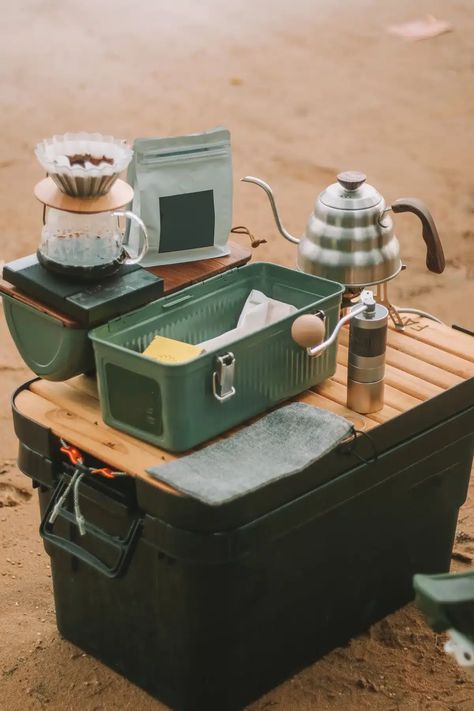 The best camping kitchens are compact and portable like the one pictured here: a dark green plastic tub with a wooden-slat top, and coffee-making supplies laid out on it. Camping Kitchen Storage, Outdoor Cooking Camping, Aesthetic Camping Set Up, Camping Things, Aesthetic Camping Gear, Coffee Camping, Japanese Camping, Camping Kitchen, Camping Inspo