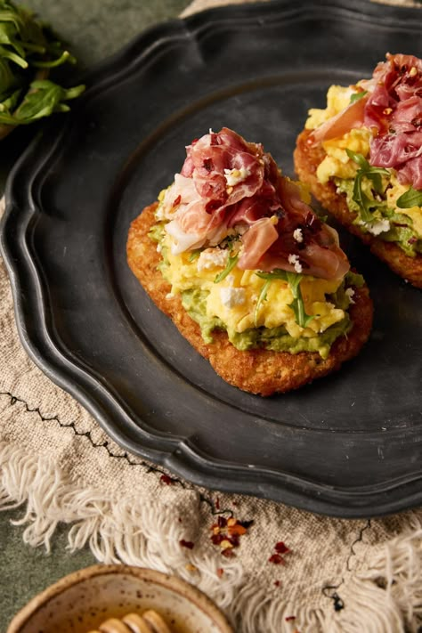 Introducing my Hashbrown Avocado Toast with Prosciutto—a delicious and satisfying breakfast or brunch option. This dish combines crispy hashbrowns, creamy avocado, prosciutto, arugula, and crumbled feta, all perfectly complemented by a drizzle of honey Eggs And Prosciutto Breakfast, Breakfast Prosciutto Recipes, Brunch Board Ideas For Two, Avocado Toast On Hashbrown, Brunch Items Easy, Late Brunch Ideas, Avocado Hashbrown Toast, Breakfast With Prosciutto, Hashbrown Skillet Breakfast