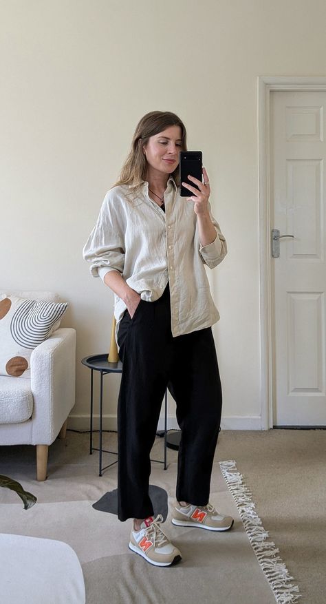 A woman stands in front of a mirror. She wears a black cord necklace, ecru oversized shirt with the sleeves pushed up, black cropped trousers and beige and orange New Balance sneakers. Crop T-shirt Outfits, Women’s New Balance 574 Outfit, Oversize Outfits Woman, Casual New Balance Outfit, New Balance Style Women Outfits, Black Pants And Sneakers Outfit, New Balance 574 Black Outfit, Oversized Outfits Summer, Cute Outfits With New Balance