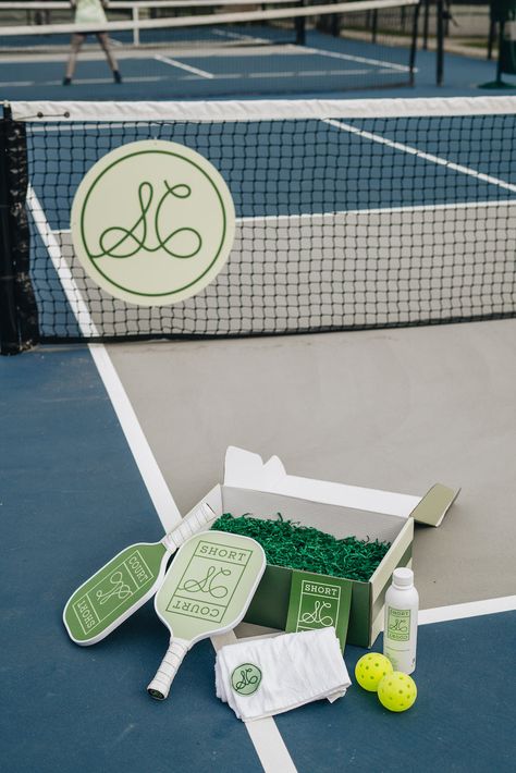 Pickleball gets elevated with South Carolina-based Short Court, offering apparel and equipment for the discerning player. Classic court values meet peak performance in this effortlessly stylish gear, ready to take you from the court to cocktails. The Courtside Collection, Doubles is a curated pickleball assortment, including two premium Short Court paddles, two custom indoor pickleballs, two deluxe court towels with the Short Court monogram, and a few Short Court stickers—plus, a matching box. P Pickle Decor, Club Branding Design, Olympic Party, Huntington Park, Summer Beach Towels, Ball Aesthetic, Pickleball Court, Sport Court, Bar Seating