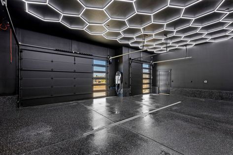 Hex lighting and black finished flooring complete this garage. High End Garage Design, All Black Garage Interior, Black Garage Walls, Dream Garage Ideas, All Black Garage, 2 Car Garage Ideas, Dream Garage Luxury, Garage Ideas Design Interior, Black Garage Interior