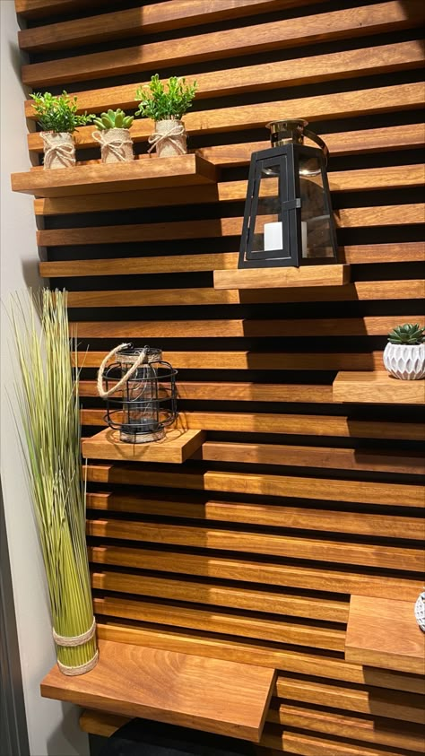 This wall design, made from black Valcromat and Iroko, brings not only nature & warmth into any room, it also can serve as a shelving unit. #walldesign #wooddesign #shelvedesign #woodwall #interiordesign Slat Wall With Moveable Shelves, Wood Slat Shelf Wall, Outdoor Wall Shelf, Wood Slate Accent Wall With Shelves, Wood Slat Shelves, Slate Wall With Shelves, Horizontal Wood Slat Wall Bedroom, Slatted Wall Shelves, Wood Wall Outside