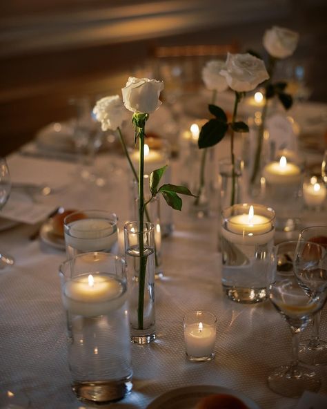 Simple single white roses and candles wedding table decor Single Stem Table Decor Wedding, Single Stem Rose Wedding Table, Light Wedding Flowers, Single Rose Centerpiece Simple, Minimalist White Rose Centerpiece, Single Rose Table Centerpiece, Tea Light Candles Wedding Centerpieces, White Flower Table Setting, Single Stem White Rose Wedding