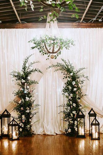 wedding altar decoration background of white cloth the altar of greenery with white flowers is surrounded by lanterns janelle sutton via instagram Wedding Alter Decorations, Wedding Altar Decorations, Winter Wedding Arch, Winter Ceremony, Indoor Wedding Ceremony, Wedding Alters, Wedding Altar, Altar Flowers, Wedding Altars