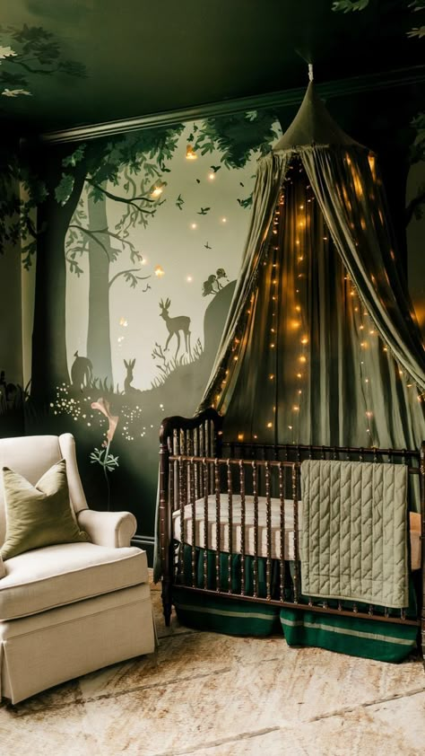 A woodland-inspired baby girl nursery featuring a forest mural with deer and rabbits, a dark wood crib with a green canopy draped in fairy lights, and earthy decor. The cozy space includes a beige rocking chair with a green pillow and a rustic, nature-inspired design. Dark Wood Crib, Woodland Fairy Nursery, Light Green Nursery, Forest Nursery Girl, Forest Baby Rooms, Forest Baby Nursery, Woodland Nursery Girl, Wood Crib, Baby Nursery Design