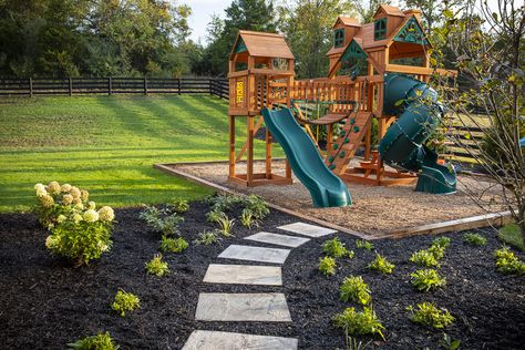 Outside children's playset and stepping stones Playset In Corner Of Yard, Play Set Landscaping Backyard Playground, Playset Landscaping Ideas, Backyard Design With Playset, Home Playground Landscaping, Playground Area Landscape, Mulch Play Area For Kids, Outdoor Playset Landscaping, Backyard With Playset