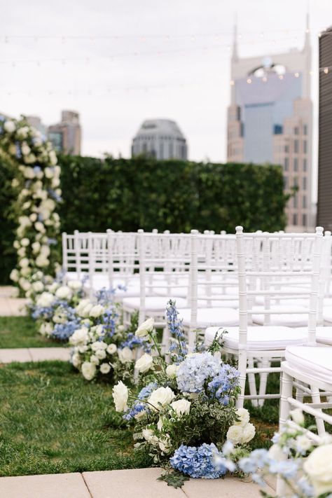 Wedding ceremony decorations for Kati & Bryant’s elegant Nashville wedding. We decorated their wedding ceremony with an elegant wedding arch, blue and white wedding flowers and hydrangeas, and white wedding chairs. Their beautiful light blue and white wedding color palette was perfect for their elegant wedding décor. We offer luxury wedding planning in Nashville and beyond. Nashville wedding venues Hydrangea Wedding Aisle, Light Blue And White Wedding, White Wedding Chairs, White Wedding Color Palette, Blue And White Hydrangea, White Hydrangea Wedding, Rooftop Wedding Ceremony, Blue Hydrangea Wedding, White Wedding Ceremony