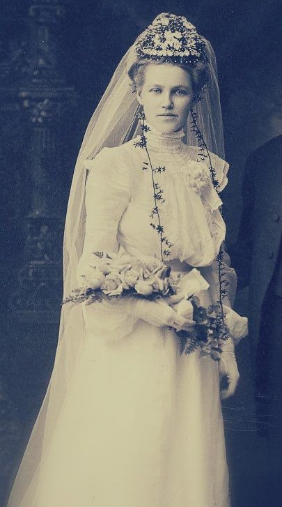 an old photo of a woman wearing a wedding dress and veil with flowers on her head