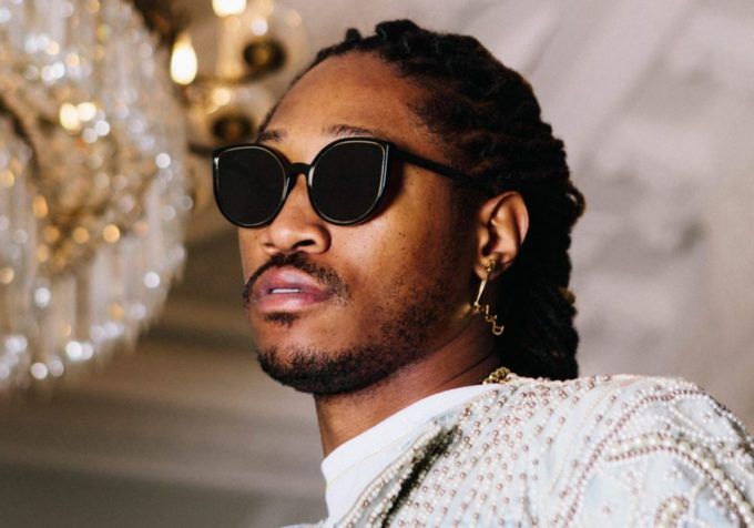 a man with dreadlocks wearing sunglasses and a white shirt in front of a chandelier