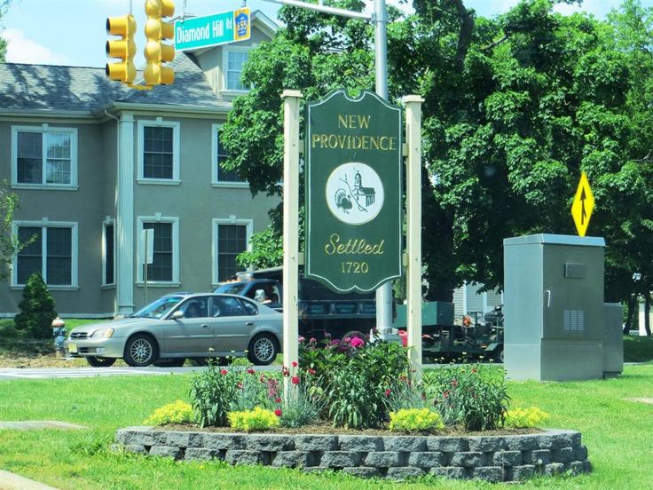 a street sign in front of a large building with cars parked on the side of it