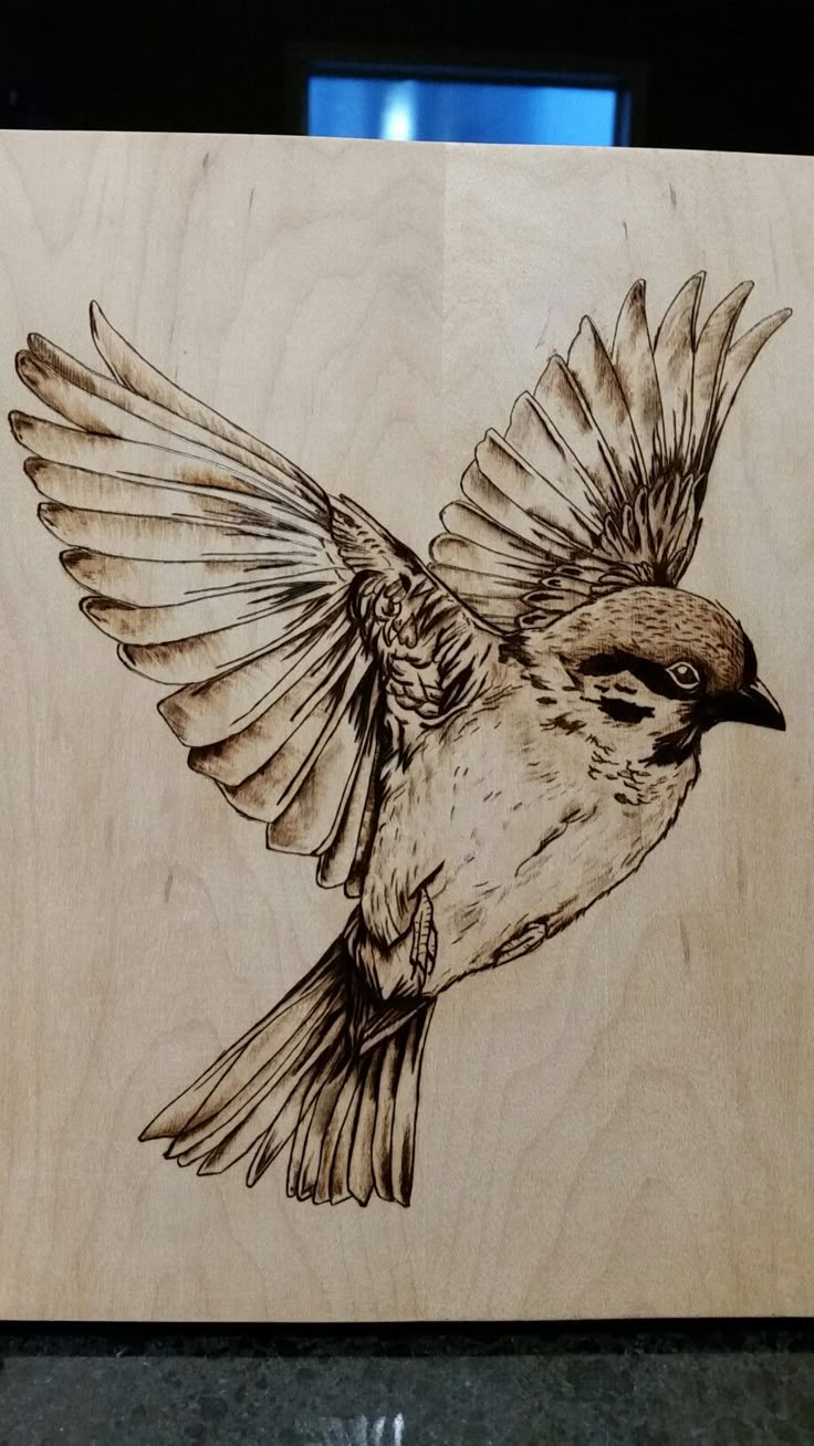 a drawing of a bird is shown on a piece of wood that has been carved into it