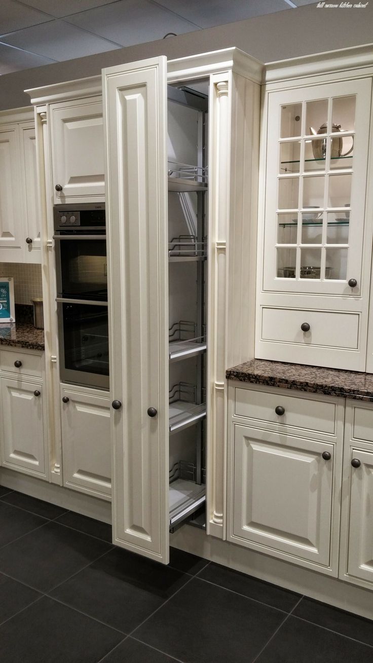 a kitchen with white cabinets and black tile flooring, including an oven in the center