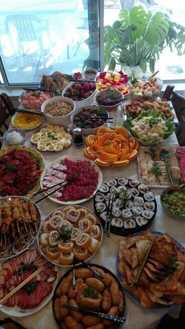 a table filled with lots of different types of food on top of plates and trays