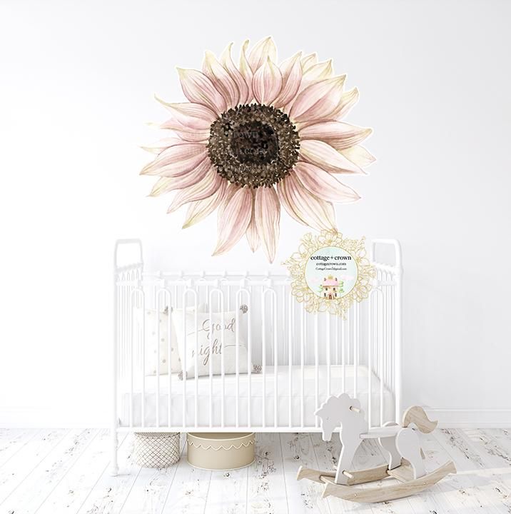 a white crib with a pink sunflower on the wall and a rocking horse next to it