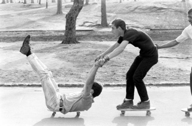 two young men riding skateboards down a street next to each other on their feet