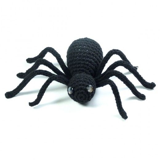 a crocheted black spider sitting on top of a white surface