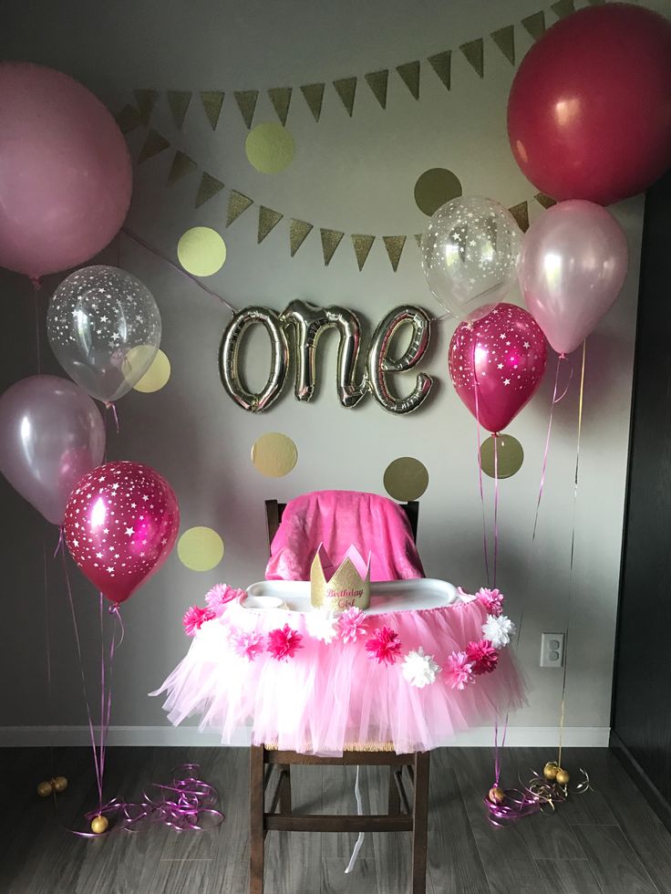 a chair with pink tutu and balloons on it in front of a wall that says one