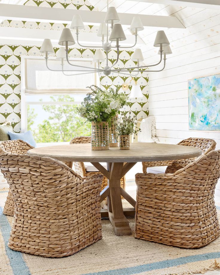 a dining room with wicker chairs and a round table in the middle of it