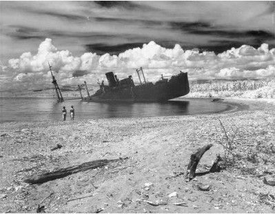 an old ship sitting on top of a beach next to the ocean