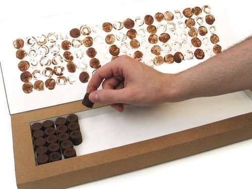 a person is making something out of chocolates on a board with buttons and holes in it