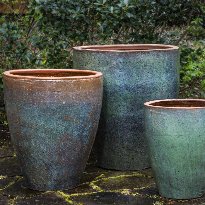 three large pots sitting on top of a stone ground