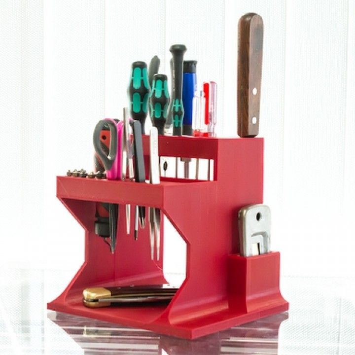 a red desk organizer with scissors and other office supplies on it's shelf,