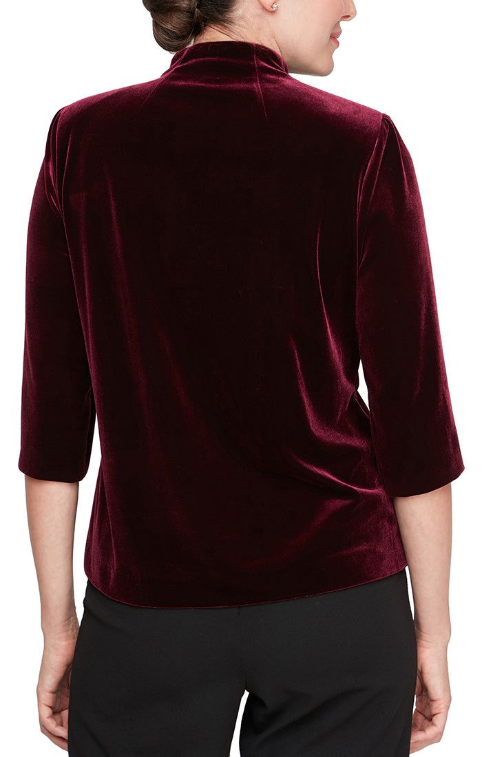 This blouse is crafted from Winter's bestselling fabric: our stretch velvet. It features 3/4 sleeves for the perfect amount of arm coverage, an asymmetric pointed hem, and a floral embellishment at the side. Pair with our black pant (style #36025) or our black skirt (style #36527) for a classy evening look. Floral Embellishment, Elegant Jacket, Polo Design, Flattering Tops, Alex Evenings, Velvet Blouses, Skirt Style, Velvet Jacket, Stretch Velvet