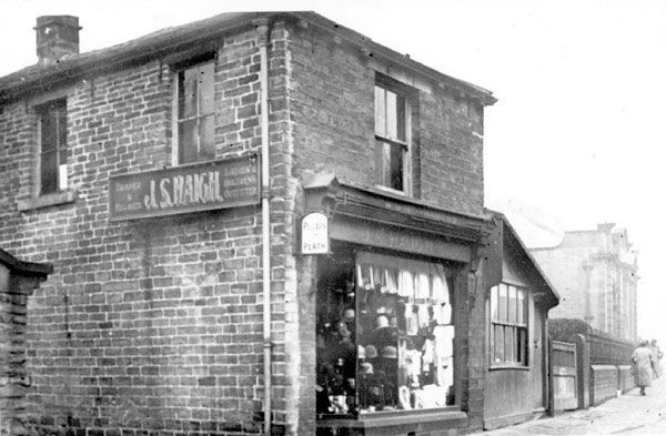 an old black and white photo of a brick building with clothes on the front window