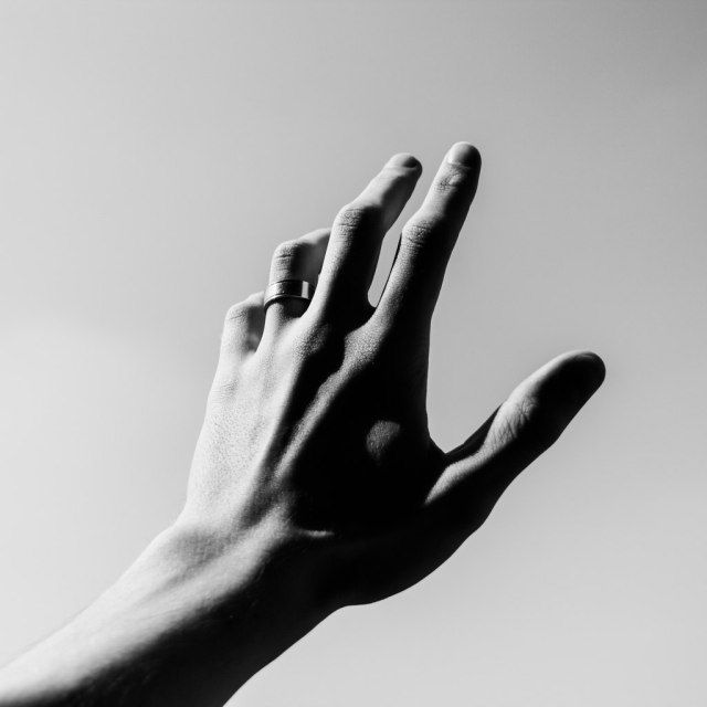 a person's hand reaching up into the sky