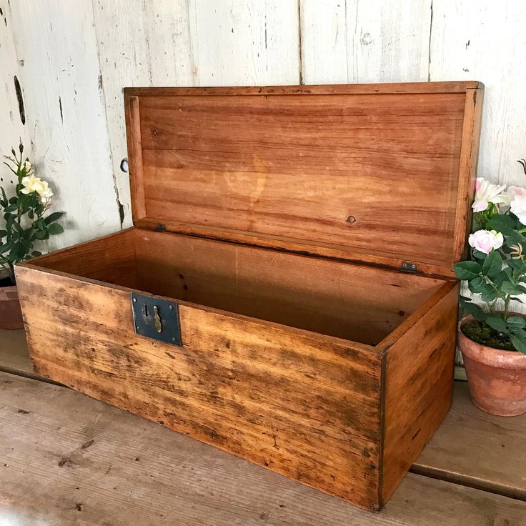 an old wooden box sitting on top of a table next to potted plants and flowers