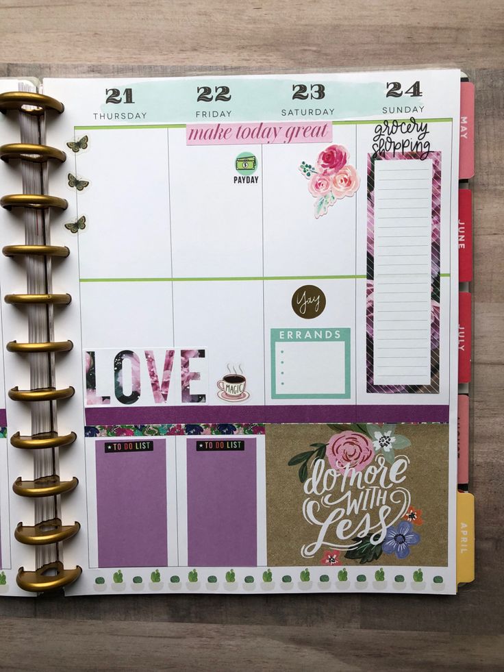 an open planner with lots of stickers on the pages and some gold clips attached to it