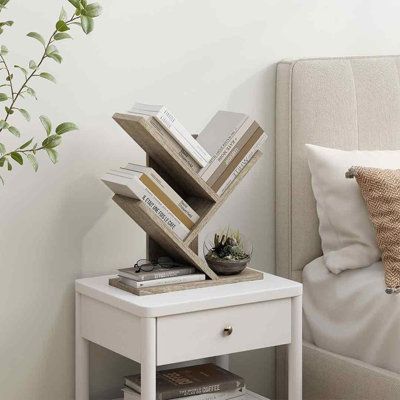 a white nightstand with books on it and a plant in the corner next to it