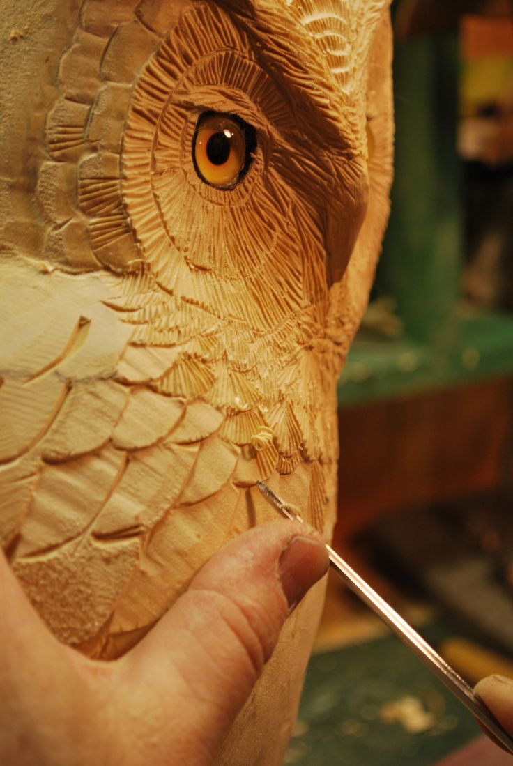 a person carving an owl's head with a pair of scissors in their hand